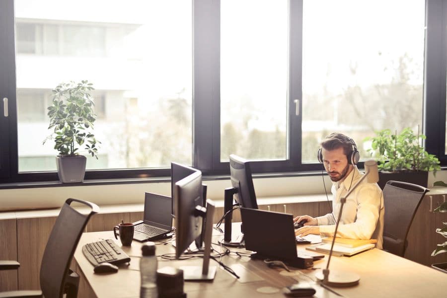 Help desk agent with a headset at a desk with plants